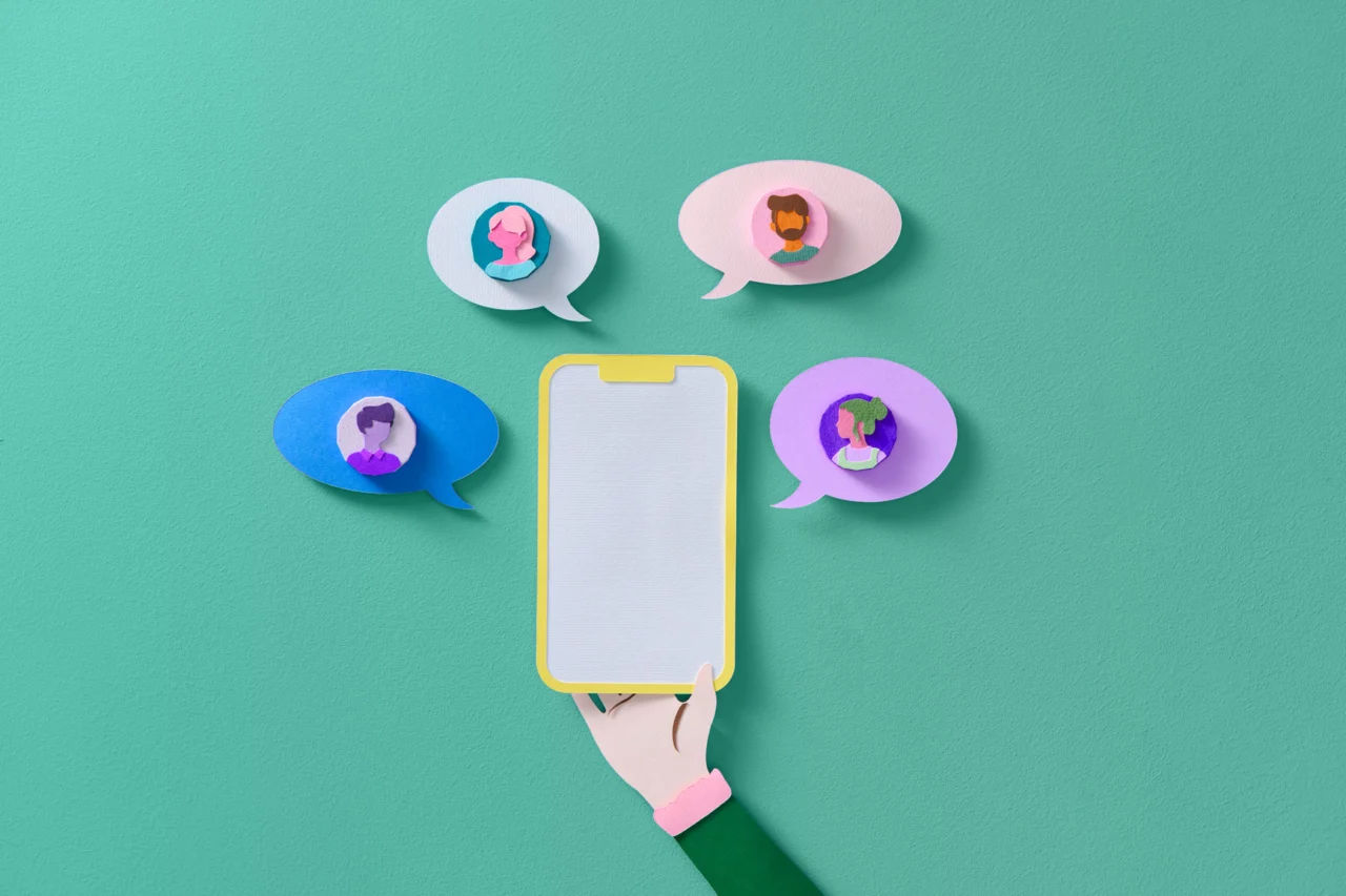 Hand hält Handy mit Sprechblasen außen drum